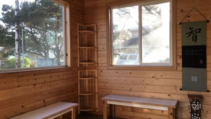 A wooden cabin interior with two benches, a wooden shelf, and a wall-mounted scroll. - Single level home, near beach. Ultra clean. Great location -Walk to everything! (Yachats)