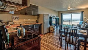A modern kitchen with a large island, stainless steel appliances, and a dining area with a view of the ocean.