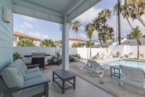 A covered patio with a pool, lounge chairs, a barbecue grill, and a seating area. - Upscale Beach Home with Private Pool & Hot Tub! Walk to Beach! (South Padre Island)