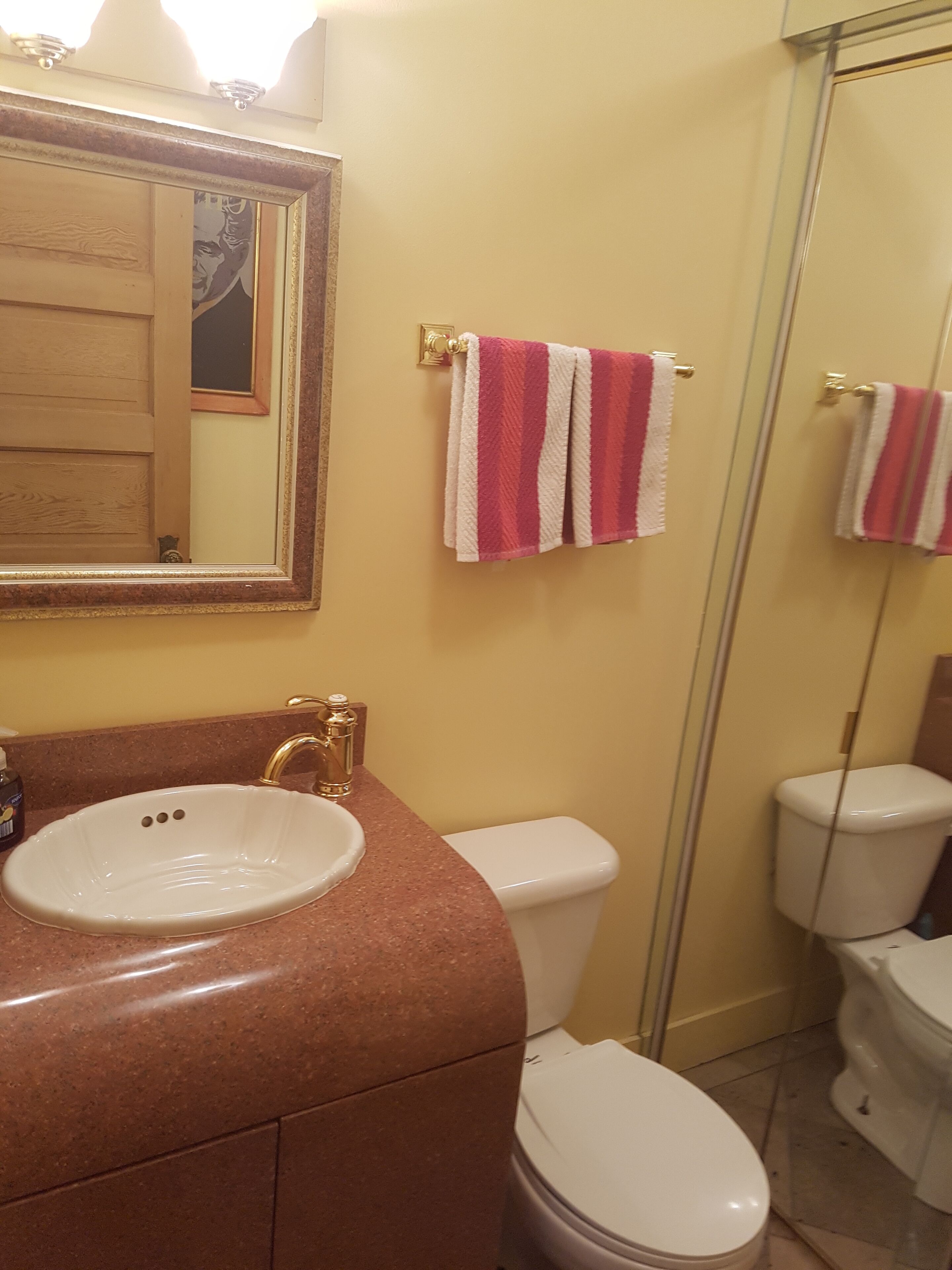 A bathroom with a sink, mirror, and two toilets.