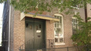 Un edificio de ladrillo con una puerta numerada, un pequeño porche y una ventana.