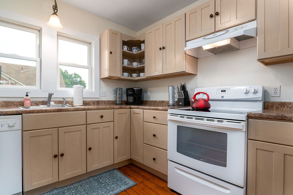 Une cuisine avec des meubles de couleur beige, une cuisinière blanche et une machine à café.