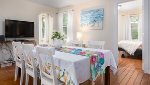 Una habitación con una mesa de comedor preparada para cuatro personas, un televisor y una cama con vistas.