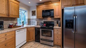 A kitchen with wooden cabinets, a stainless steel refrigerator, a microwave, an oven, and a dishwasher. - Inside Yosemite Park-Yosemite Spring Wonderland (Yosemite National Park)
