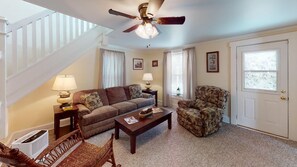 A living room with a sofa, armchair, coffee table, and a ceiling fan.