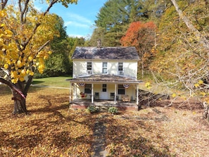 A two-story house with a porch, surrounded by autumn foliage.