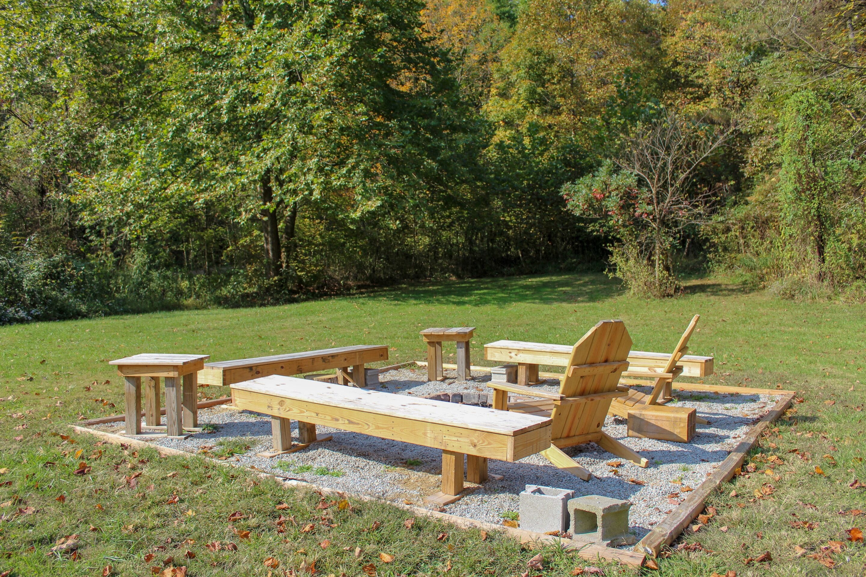 A picnic area with wooden benches and tables surrounded by trees.