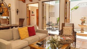 A living room with a sofa, a coffee table, and a chair. There is a dining table and chairs in the background. - Beautiful and Cozy  Home in Loreto Bay, close from pool and wine bar (Loreto)