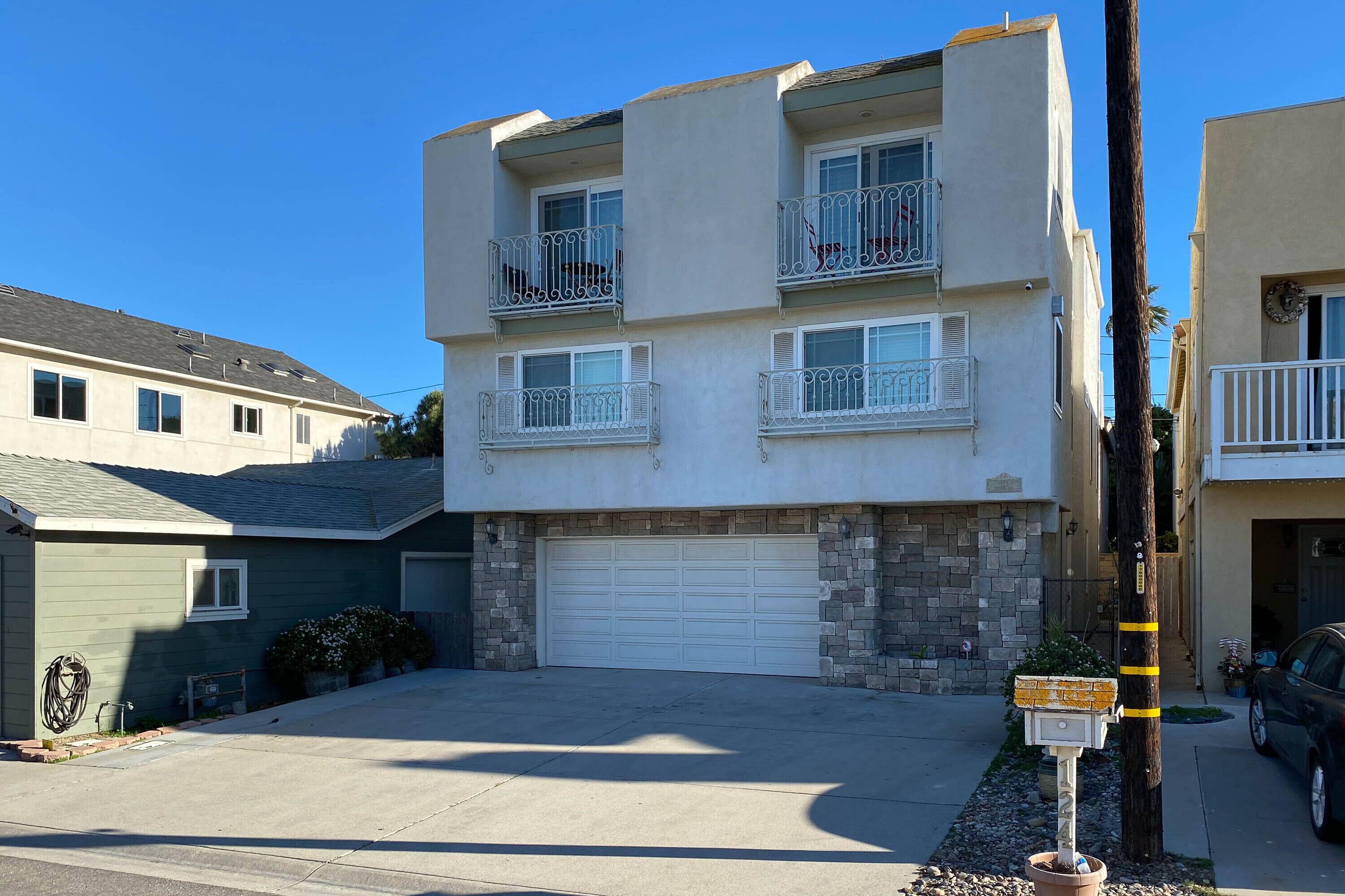 A two-story residential building with a garage, balconies, and a clear driveway.