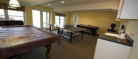 Una habitación con cama, mesa de ping pong y una pequeña kitchenette.
