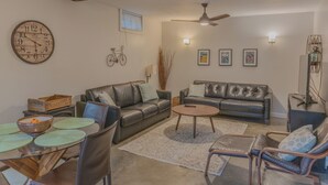 Ein Wohnzimmer mit einer Holz-Uhr, zwei Ledersofas, einem Couchtisch und einem Esstisch mit Stühlen.