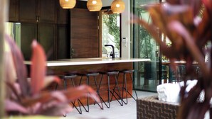 Une cuisine moderne avec des meubles de couleur bois foncé, un îlot central doté de tabourets de bar et un éclairage suspendu.