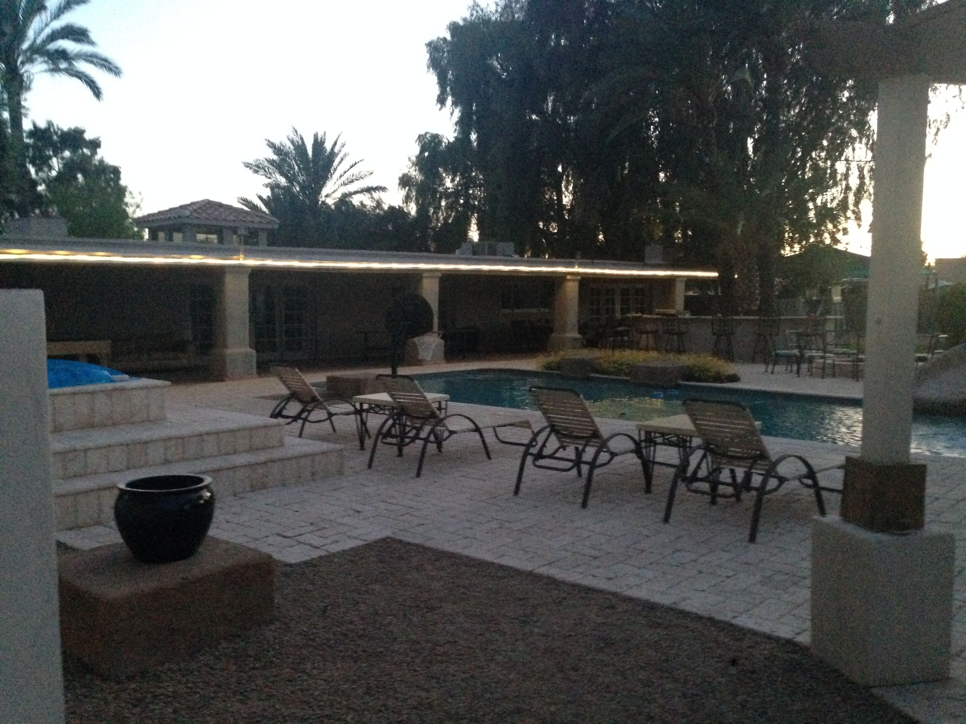 A pool area with lounge chairs and a pergola.