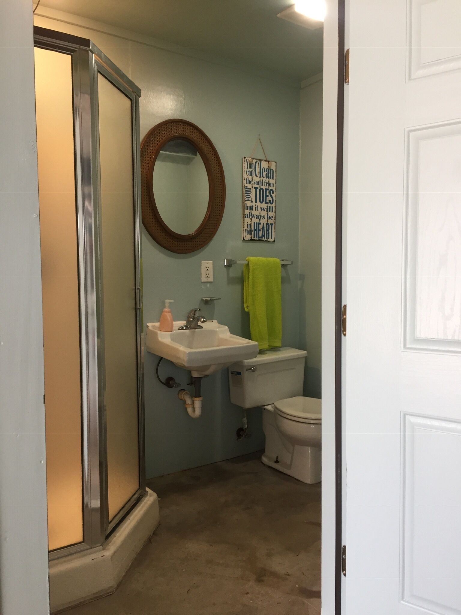 Een badkamer met een douche, wastafel, toilet en een spiegel.