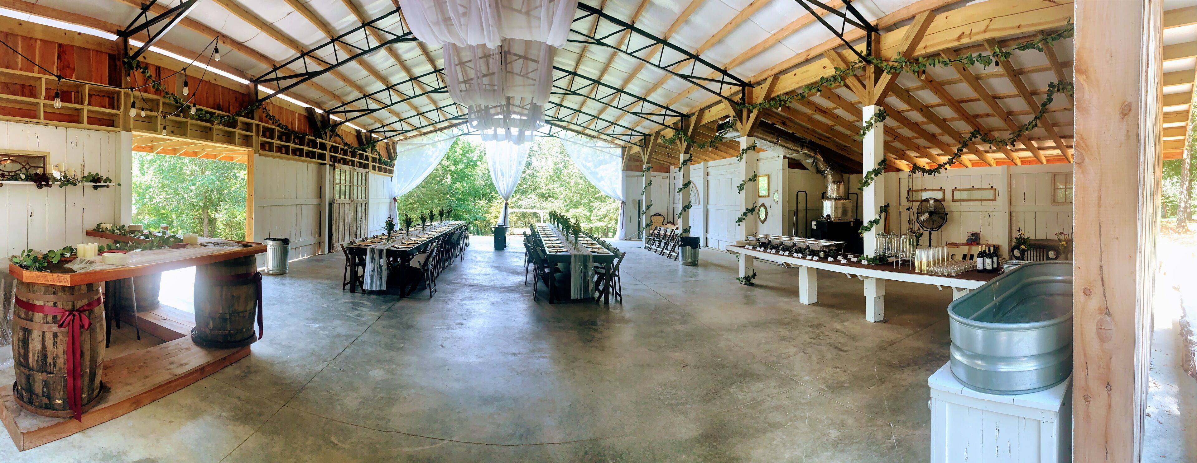 Un vaste espace de restauration couvert, doté de longues tables, de poutres en bois et de plantes suspendues.