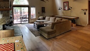 A spacious living room with a stone fireplace, a wooden ceiling, and a large window. - Winter wonderland perfect for multiple families- 3 master bedrooms! (Truckee)