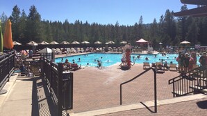 A pool area with lounge chairs and umbrellas, surrounded by a forested area. - Winter wonderland perfect for multiple families- 3 master bedrooms! (Truckee)