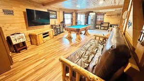 Ein Holzinterieur mit Billardtisch, Ledersofa und Fernseher.