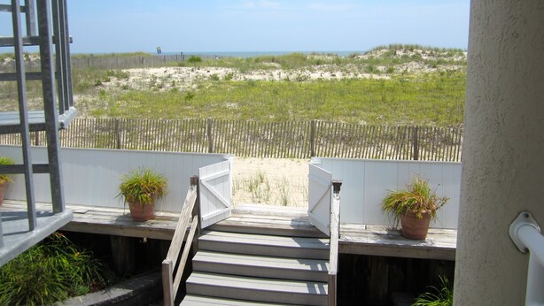 A wooden staircase leading to a balcony with a view of a sandy beach and dunes. - Oceanfront 12 Bedroom 8 Bath in Ocean City, New Jersey (Ocean City)