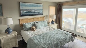 A bedroom with a large bed, two bedside tables with lamps, a painting on the wall, and a view through the window. - Oceanfront 12 Bedroom 8 Bath in Ocean City, New Jersey (Ocean City)