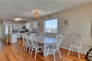 Una cocina con armarios blancos, una mesa de comedor con sillas blancas y vistas a la ciudad a través de una ventana.