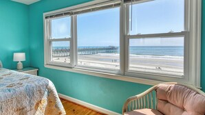A room with a large window, a bed, a chair, and a nightstand. - Against The Wind A, Oceanfront Home, Amazing Pier View, Duplex (Garden City Beach)