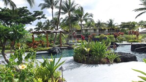Ein tropisches Resort mit Poolanlage, Palmen, einer Holzpergola und einem Schild mit der Aufschrift 'Kapo'.