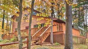 A rustic cabin with a wooden exterior, a deck, and a staircase leading to the entrance. - Executive Year Round Home ~ Minutes From  Minocqua (Arbor Vitae)
