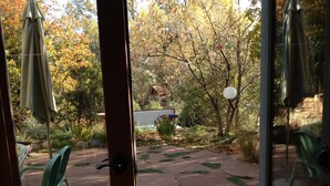 A patio with a stone floor, outdoor furniture, and a view of trees and a building in the background. - Unsurpassed Night Skies And Fresh Mountain Air In A Traditional Village (Santa Fe)