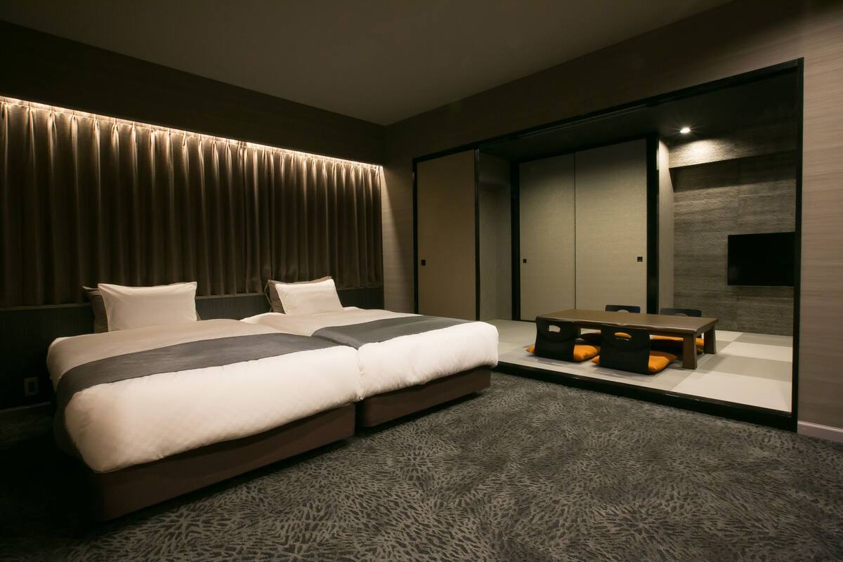 Una habitación de hotel moderna con una cama grande, un escritorio con sillas y un armario con puerta corredera.