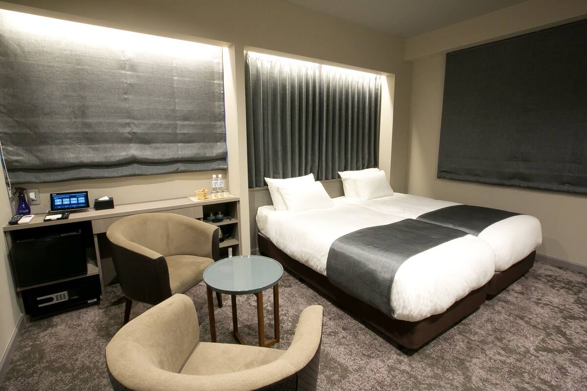 Habitación de hotel con una cama, un escritorio con computadora, una silla y una mesita.