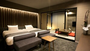 Una habitación de hotel con una cama grande, dos sofás, una mesita y un armario con puerta corredera.
