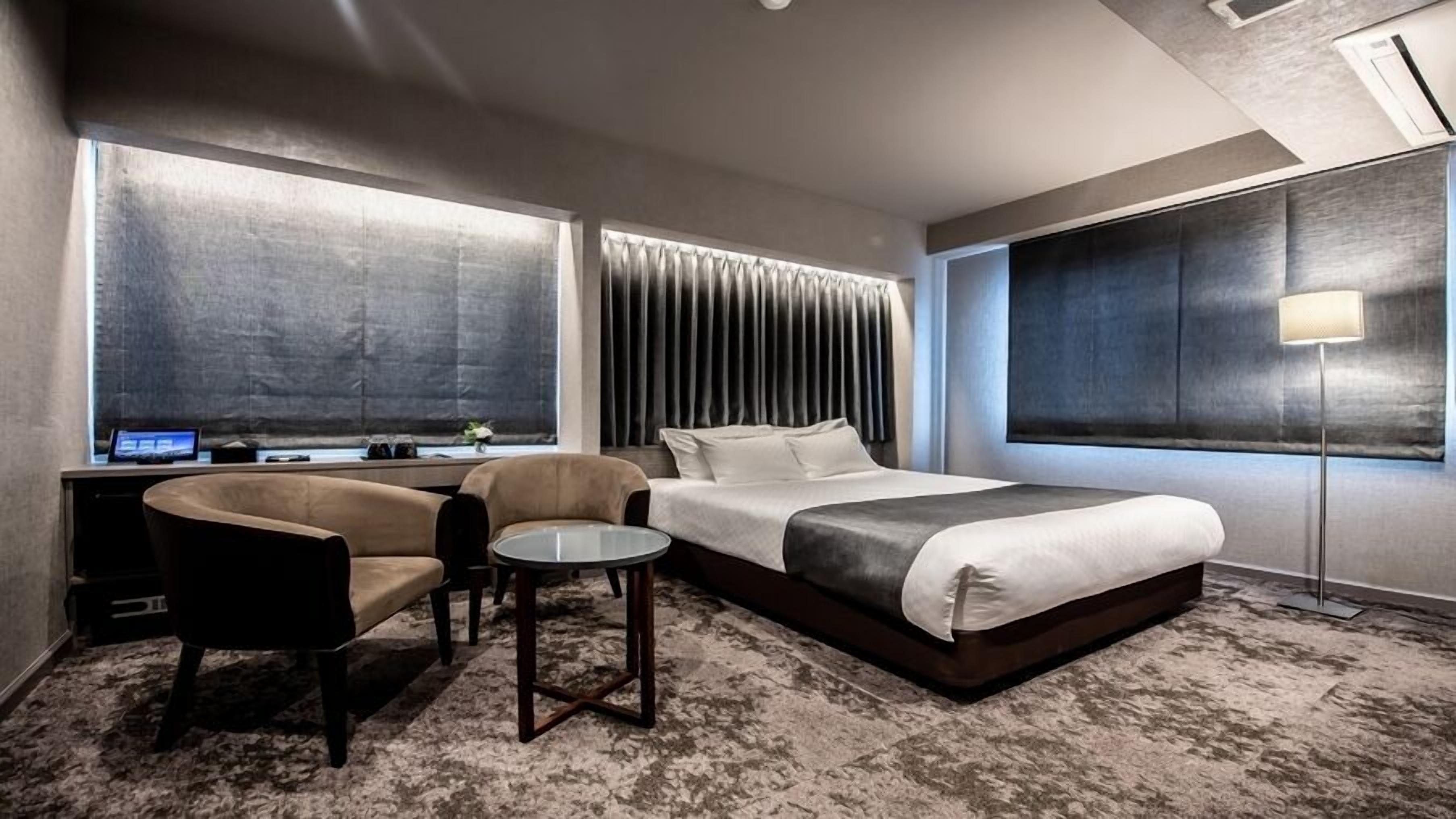 Et moderne hotelværelse med en stor seng, et skrivebord med en computer, en stol og et lille bord.