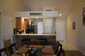 Una cocina compacta con comedor, un cartel sobre la encimera y una puerta que da a otra habitación.
