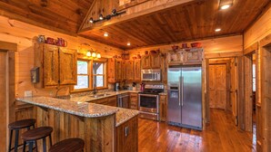 Una cocina con armarios de madera, un refrigerador de acero inoxidable, un microondas y una encimera de granito.