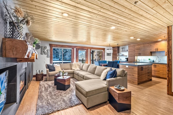 A modern living room with a large sectional sofa, a fireplace, and a view of the outdoors.
