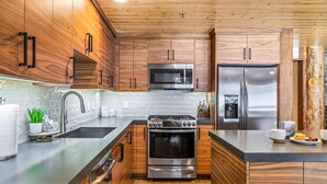Eine moderne Küche mit Holzschränken, Edelstahlgeräten und einer Arbeitsplatte aus Granit.