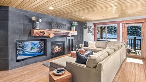 Ein gemütliches Wohnzimmer mit Kamin, großem Fernseher und bequemer Couch.