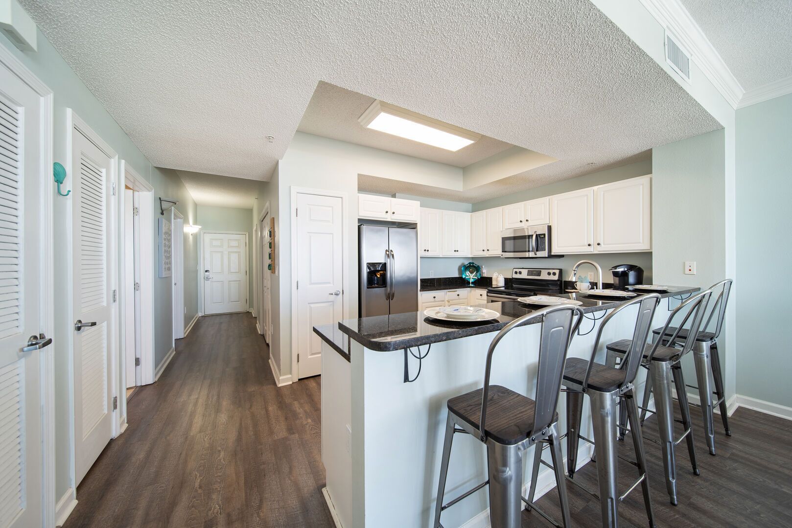 A modern kitchen with white cabinets, stainless steel appliances, and a central island with bar stools.