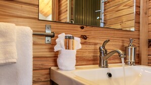 Un bagno con una parete in legno, un lavandino bianco, un asciugamano e articoli da toilette.