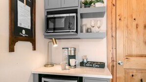 Un angolo cottura con forno a microonde, macchina del caffè e insegna con la scritta 'coffee bar'.