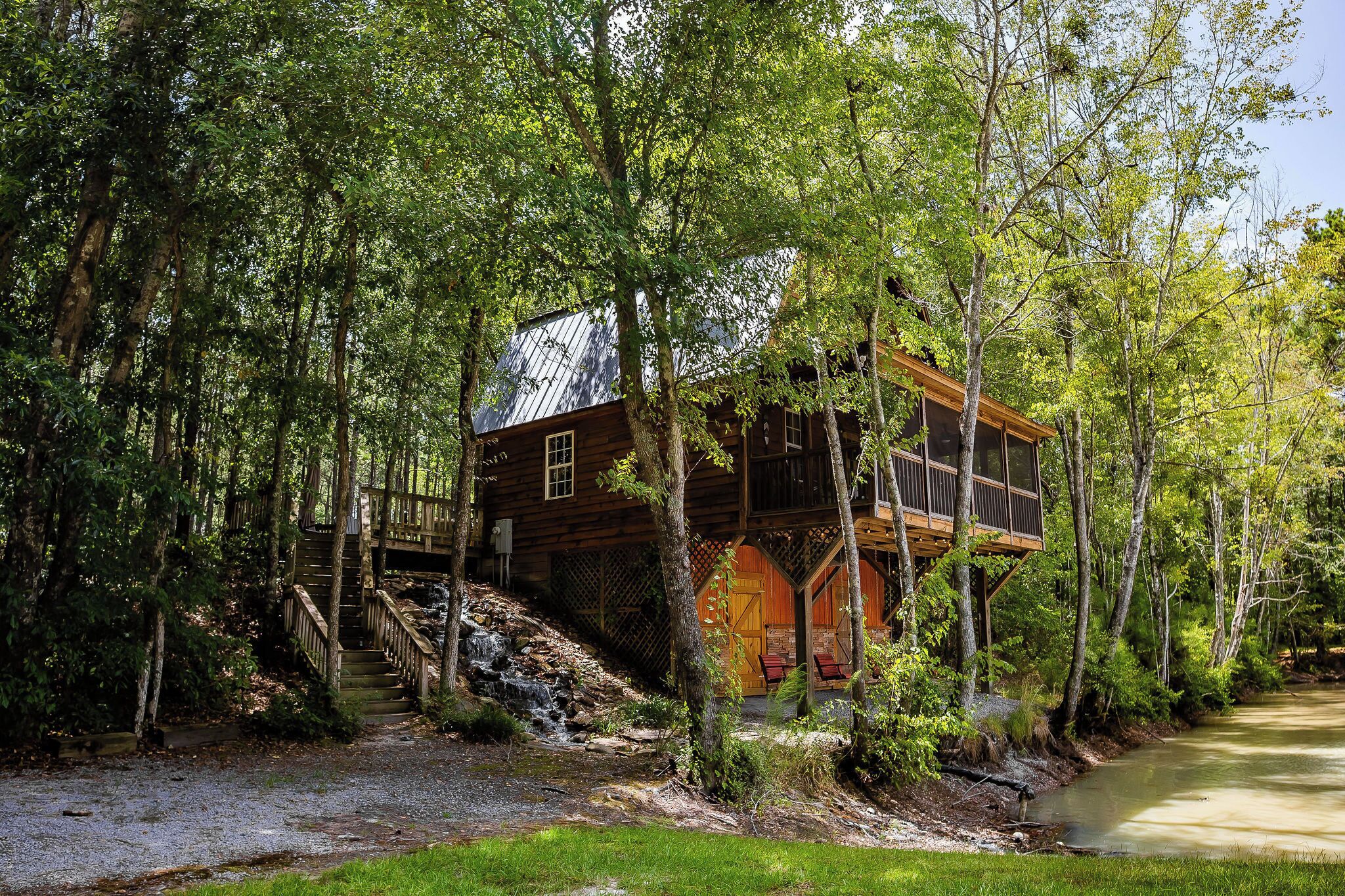 A cabin surrounded by trees with a wooden staircase leading up to it.