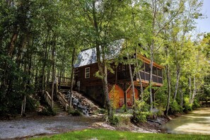 A cabin surrounded by trees with a wooden staircase leading up to it. - Hideaway Haven – A Private Retreat on 100 Acres (Marion)