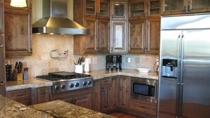 A kitchen with wooden cabinets, a stainless steel stove, a refrigerator, and granite countertops. - Spectacular Torreon Mountain Estate (Show Low)