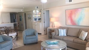 A living room with a sofa, armchairs, a coffee table, and a dining area with chairs and a table. - Peaceful, Beach-front Escape in Orange Beach! 3/3 with pool and more! (Orange Beach)