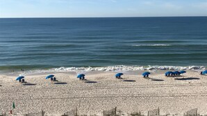 A beach with rows of blue umbrellas and beach chairs, a sandy shore, and the ocean in the background. - Peaceful, Beach-front Escape in Orange Beach! 3/3 with pool and more! (Orange Beach)