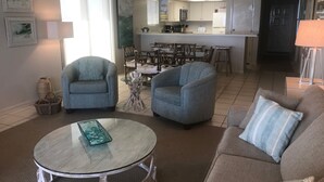 A living room with two sofas, a glass coffee table, and a dining area with chairs and a table. - Peaceful, Beach-front Escape in Orange Beach! 3/3 with pool and more! (Orange Beach)