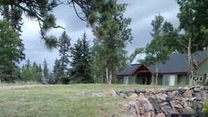 A landscaped area with a stone retaining wall, grass, and pine trees. - Modern Home Secluded in the Mountains With Breathtaking Views in Divide CO (Divide)