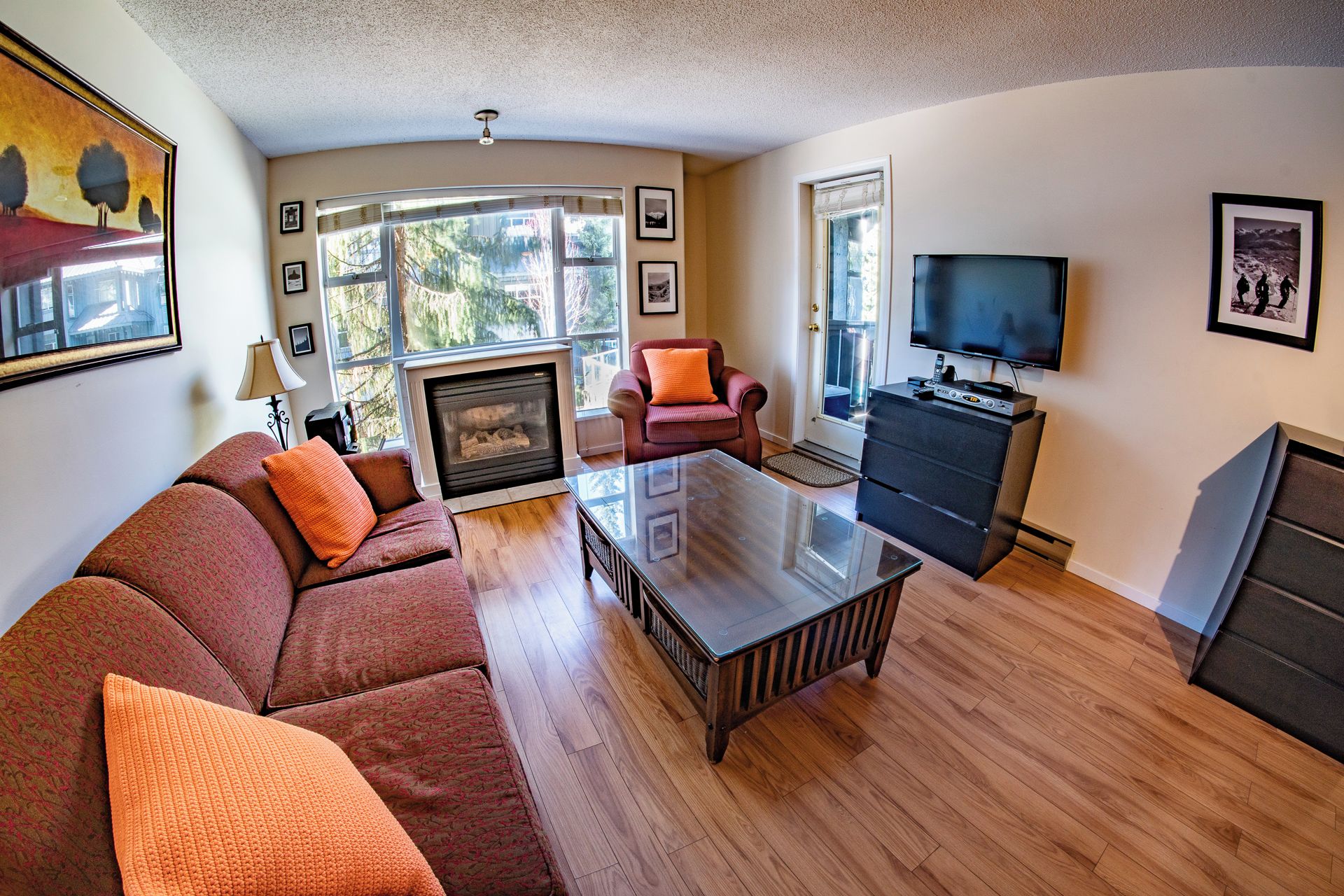 A living room with a sofa, coffee table, fireplace, television, and a fireplace mantel.