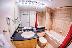 A bathroom with a sink, mirror, towel rack, hairdryer, and shower area.